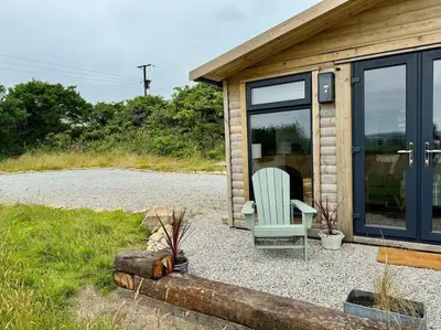 a green chair sitting outside of a cabin at Willow Lodge in Helston