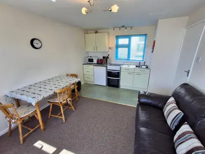 a living room with a couch and a table and a kitchen at Loe Bar Bottom in Porthleven