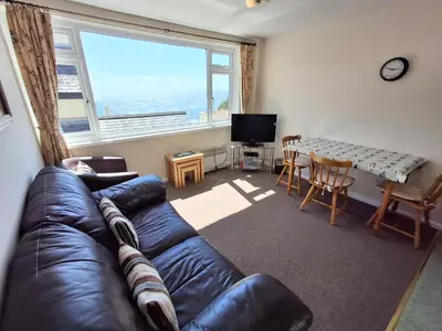 a living room with a leather couch and a table at Loe Bar Bottom in Porthleven