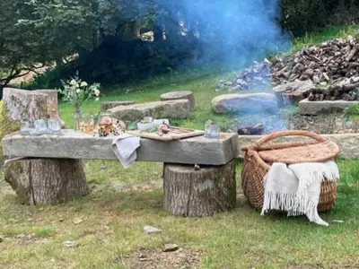 a picnic table with a picnic basket next to a fire at Tregrylls Barton in Boscastle