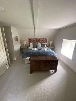 a bedroom with a bed and a table and a window at Tregrylls Barton in Boscastle