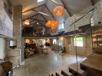 a large room with a stone wall and chandeliers at Tregrylls Barton in Boscastle