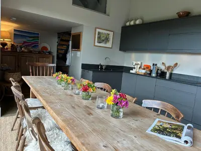 a wooden table with flowers on it in a kitchen at Tregrylls Barton in Boscastle