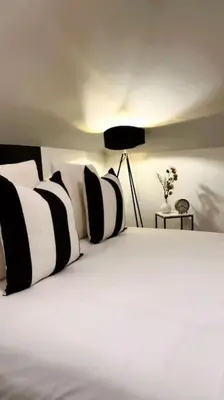 a bed with black and white pillows and a lamp at St Mary's Mews in Truro