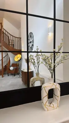 a living room with a mirror and a vase with flowers at St Mary's Mews in Truro