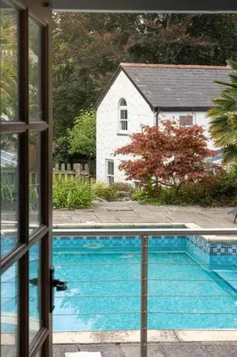 a view of a swimming pool from a window at Beautiful Country Farmhouse Set In A Stunning Woodland With Pool, Sauna & Parking at 'The Old Farmhouse' in Ponsanooth