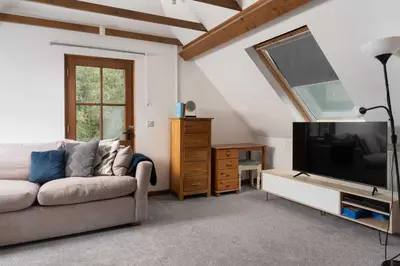 a living room with a couch and a flat screen tv at Beautiful Country Farmhouse Set In A Stunning Woodland With Pool, Sauna & Parking at 'The Old Farmhouse' in Ponsanooth