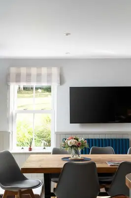a dining room with a table with chairs and a television at Beautiful Country Farmhouse Set In A Stunning Woodland With Pool, Sauna & Parking at 'The Old Farmhouse' in Ponsanooth