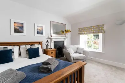 a bedroom with a bed and a chair and a fireplace at Beautiful Country Farmhouse Set In A Stunning Woodland With Pool, Sauna & Parking at 'The Old Farmhouse' in Ponsanooth