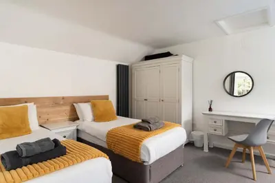 a bedroom with two beds and a desk and a chair at Beautiful Country Farmhouse Set In A Stunning Woodland With Pool, Sauna & Parking at 'The Old Farmhouse' in Ponsanooth