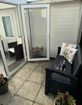 a screened porch with a bench and a sliding glass door at Cosy 1 bed apartment near Crantock beach in Crantock