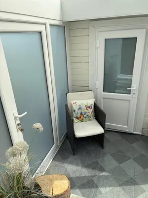 a white chair with a pillow sitting on a porch at Cosy 1 bed apartment near Crantock beach in Crantock