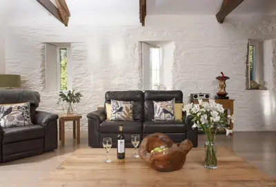 a living room with a couch and a table with wine glasses at Hob Nob in Liskeard