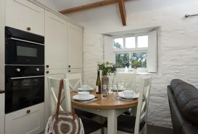 a kitchen and dining room with a table and chairs at Rainbow Cottage in Liskeard