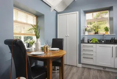 a dining room with a wooden table and chairs at Honey Pot in Liskeard