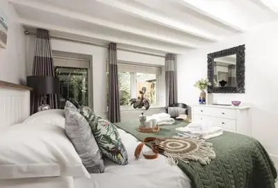 a bedroom with a white bed and a mirror at Spice Barn in Liskeard