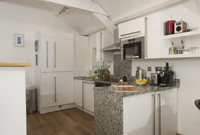 a kitchen with white cabinets and a counter top at Spice Barn in Liskeard