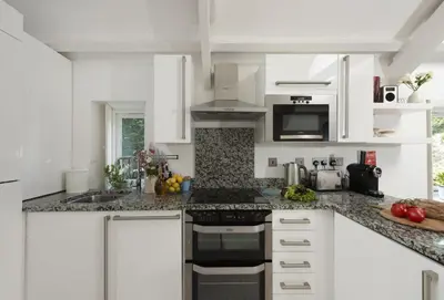 a kitchen with white cabinets and a stove top oven at Spice Barn in Liskeard