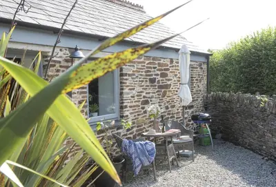 a patio with a table and chairs and an umbrella at Spice Barn in Liskeard