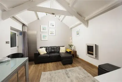 a living room with a black couch and a tv at Spice Barn in Liskeard