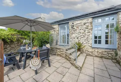 a patio with a table and an umbrella at Blackberry Barn in Liskeard