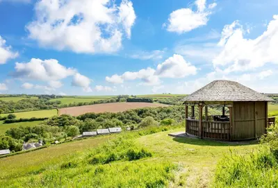 a wooden gazebo on a hill with a field at Blackberry Barn in Liskeard