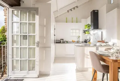a kitchen with white cabinets and a table with chairs at Blackberry Barn in Liskeard