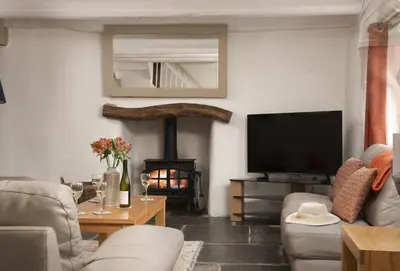 a living room with a television and a fireplace at The Old Farmhouse in Liskeard