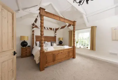 a bedroom with a canopy bed and a window at The Old Farmhouse in Liskeard