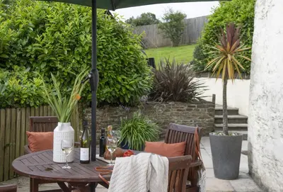 a wooden table with an umbrella on a patio at The Old Farmhouse in Liskeard
