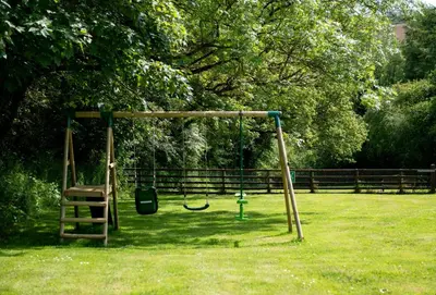a swing set in a park with a grass field at The Old Farmhouse in Liskeard