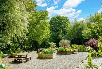 a garden with tables and benches and trees at The Old Farmhouse in Liskeard