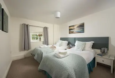 a bedroom with two beds and a window at The Old Farmhouse in Liskeard