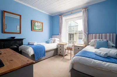 two beds in a room with blue walls at Atlantic View, North Cornwall seafront, 5* Gold in Polzeath