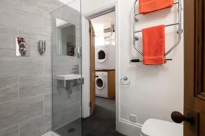 a bathroom with a shower and a washing machine at Atlantic View, North Cornwall seafront, 5* Gold in Polzeath