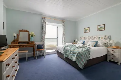 a bedroom with a bed and a desk and a mirror at Atlantic View, North Cornwall seafront, 5* Gold in Polzeath