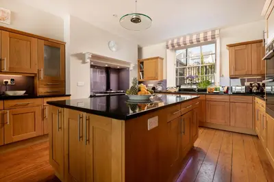 a large kitchen with wooden cabinets and a black counter top at Atlantic View, North Cornwall seafront, 5* Gold in Polzeath