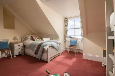 a small attic bedroom with a bed and a window at Atlantic View, North Cornwall seafront, 5* Gold in Polzeath