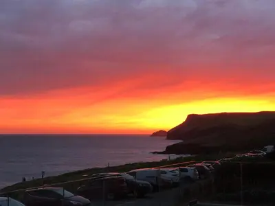 a sunset with cars parked in a parking lot at Atlantic View, North Cornwall seafront, 5* Gold in Polzeath