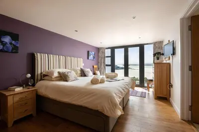 a bedroom with a large bed with a purple wall at Atlantic View Coach House, North Cornwall seafront, 5 star Gold in Polzeath