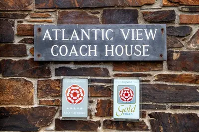 a sign on the side of a brick wall at Atlantic View Coach House, North Cornwall seafront, 5 star Gold in Polzeath