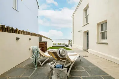 a patio with two chairs and a table on a balcony at Atlantic View Coach House, North Cornwall seafront, 5 star Gold in Polzeath