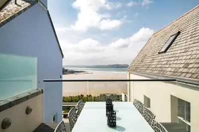 a view of the beach from the balcony of a house at Atlantic View Coach House, North Cornwall seafront, 5 star Gold in Polzeath