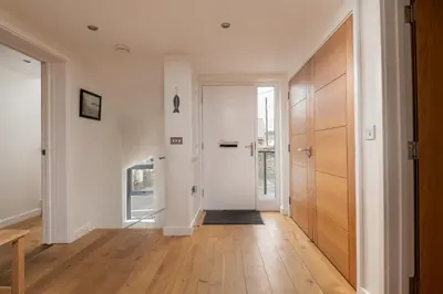 a hallway with white walls and a wooden door at Atlantic View Coach House, North Cornwall seafront, 5 star Gold in Polzeath