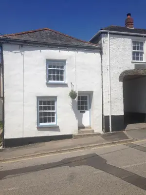 a white house with two windows on a street at Cosy Traditional Cornish Cottage in Tregoney