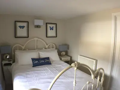 a bedroom with a bed with a blue pillow on it at Cosy Traditional Cornish Cottage in Tregoney