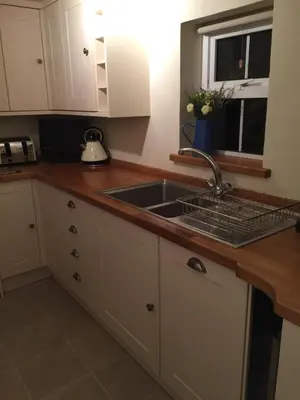 a kitchen with white cabinets and a sink at Cosy Traditional Cornish Cottage in Tregoney