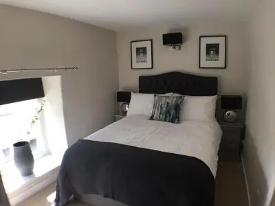 a bedroom with a large bed and a window at Cosy Traditional Cornish Cottage in Tregoney