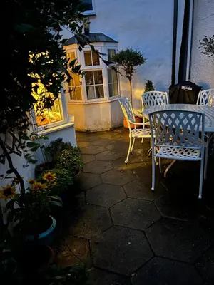 a patio with two chairs and a table and a window at Cosy Traditional Cornish Cottage in Tregoney