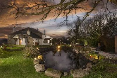 a church and a pond in front of a house at Worvas Counthouse - Country Cottage - Hot Tub - Pet Friendly in St Ives